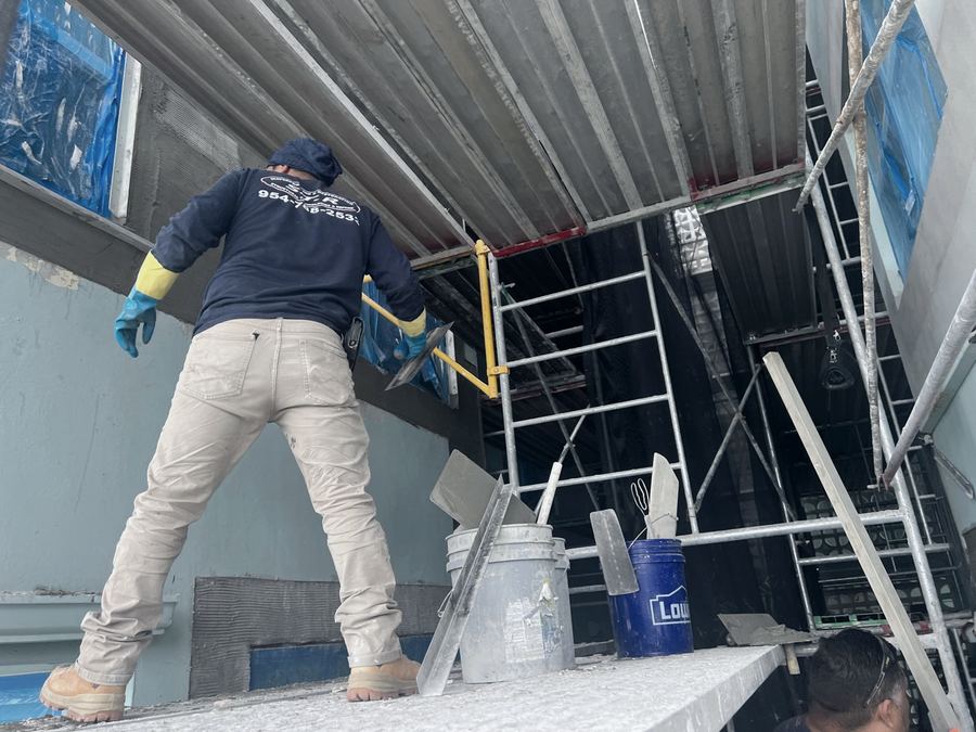Waterproofing and stucco work on a building facade from scaffolding
