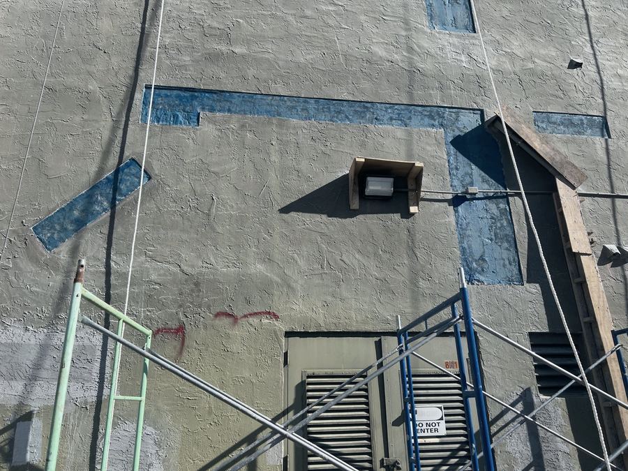Stucco and concrete patch repairs marked across a facade